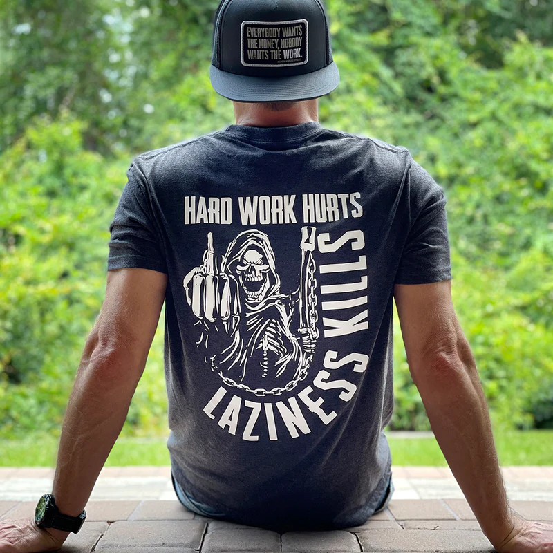 Man wearing graphic tee with motivational message, sitting outdoors.